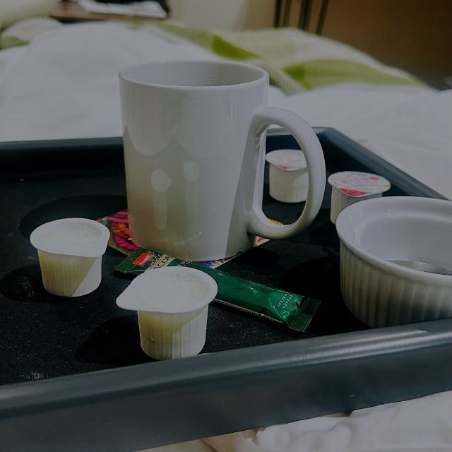 A white coffee mug, creamer pods, and instant coffee on a black hospitality tray inside a guest room at Indaba Hotel Spa and Conference Centre in Johannesburg.