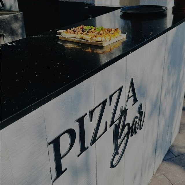 A freshly baked pizza on a wooden board displayed on the black marble counter of an outdoor Pizza Bar at Indaba Hotel Spa and Conference Centre in Johannesburg.