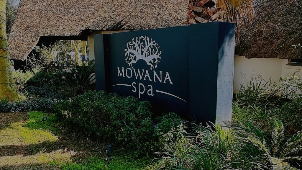 The exterior entrance sign displaying the Mowana Spa logo surrounded by lush garden greenery at Indaba Hotel Spa and Conference Centre in Johannesburg.