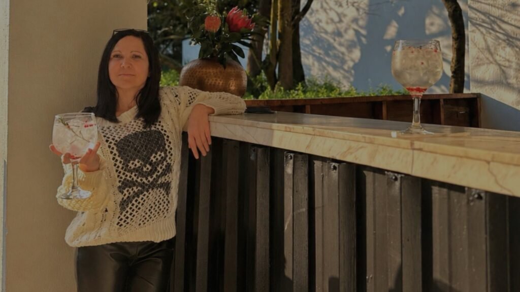 Claudia Sherrin posing with a garnished gin and tonic glass while leaning on a marble-topped bar at Indaba Hotel Spa and Conference Centre in Johannesburg.