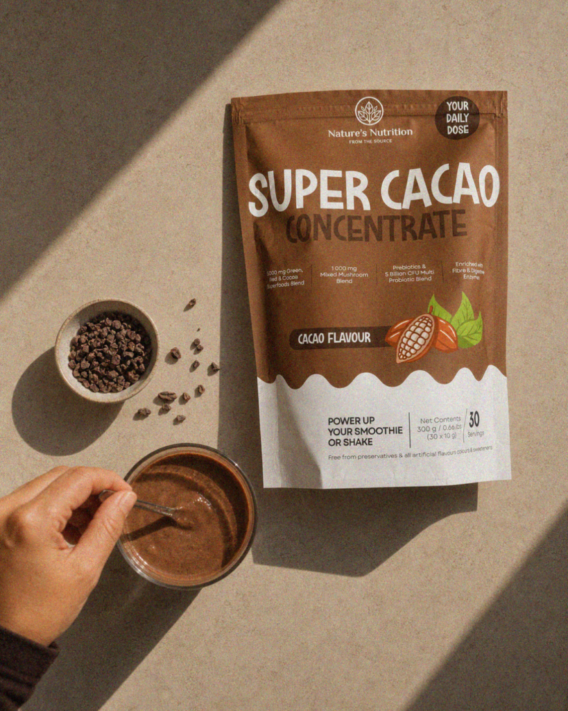 Nature's Nutrition Super Cacao Concentrate pouch next to a bowl of cacao nibs and a freshly mixed smoothie.