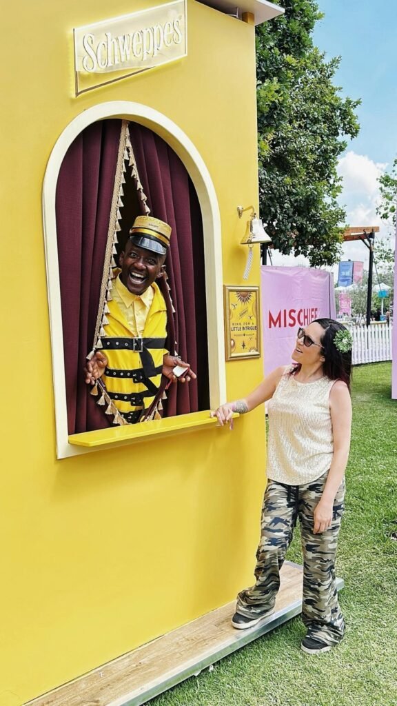 A friendly event host in a yellow Schweppes costume interacting with a guest from a yellow booth installation at the Luxurious Marble Circus.
