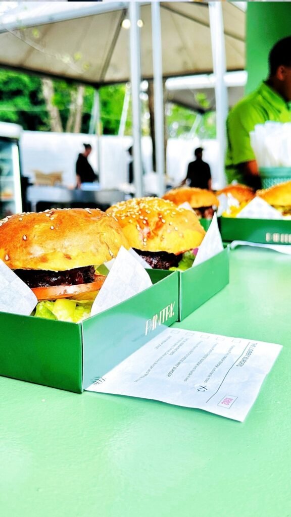 Freshly prepared gourmet burgers in branded green boxes from The Pantry food area at the Luxurious Marble Circus event.