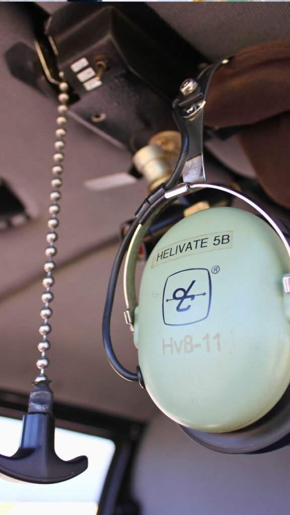 Close-up of a light green Helivate-branded aviation headset hanging inside the helicopter cabin, labelled Helivate 5B.