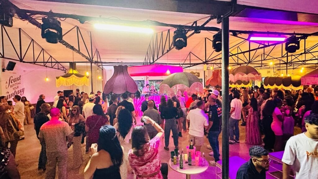 A lively crowd gathered inside an ambiently lit indoor stage area featuring oversized lampshades at the Luxurious Marble Circus.