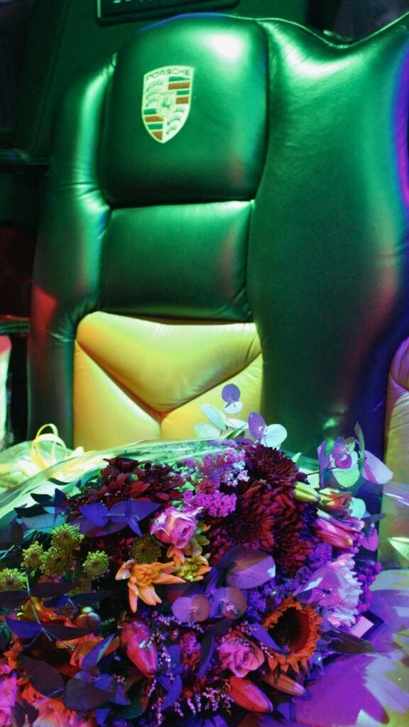 Green neon-lit Porsche leather seat inside Luxury Limousines with vibrant floral bouquet in the foreground