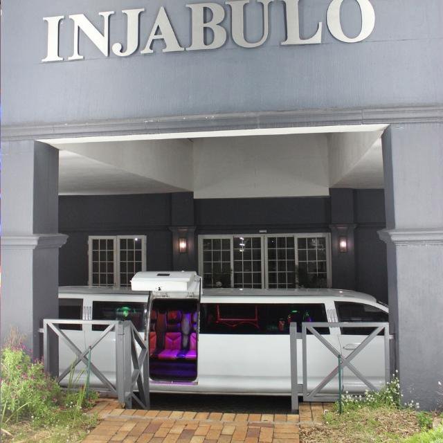 White stretch limousine parked under the Injabulo entrance with doors open, ready for arrival or departure