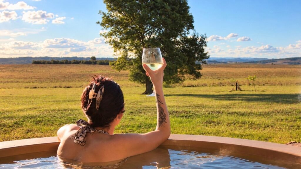 Claudia relaxing in the fire-heated hot tub with a glass of wine overlooking the Magaliesberg at Sibani Lodge