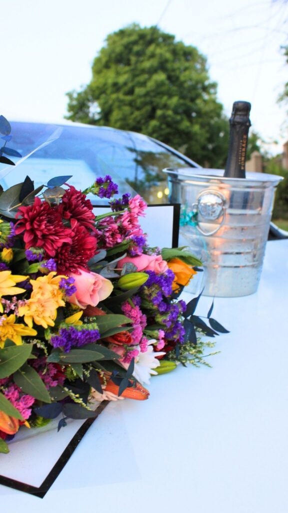 Colourful flower bouquet and chilled Pongrácz champagne in silver ice bucket resting on the white Porsche Cayenne limousine bonnet