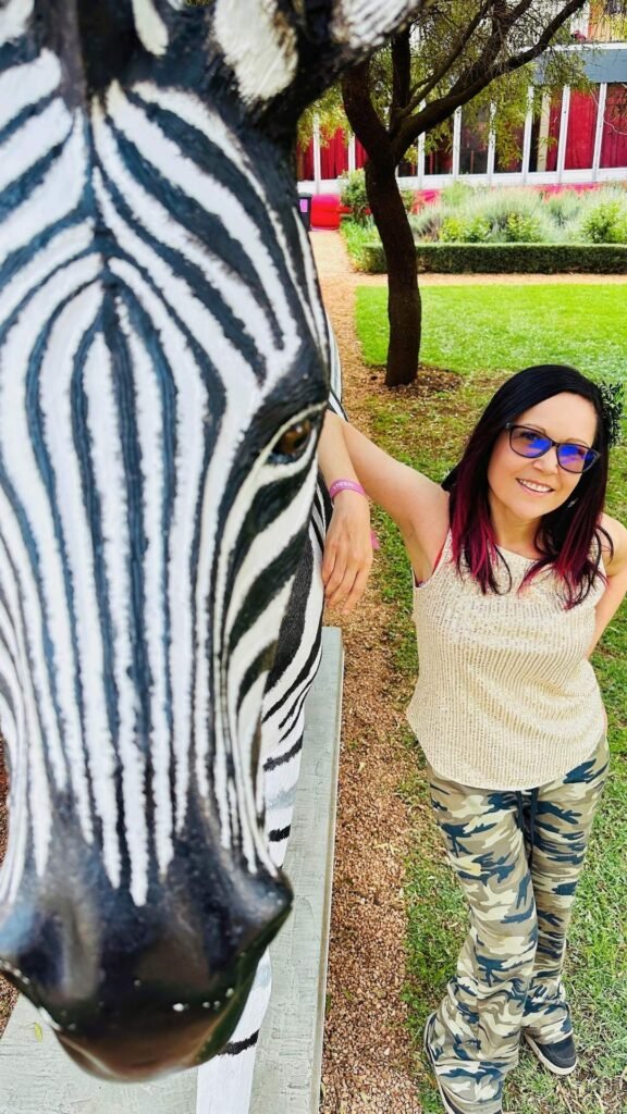 Claudia posing next to a striking zebra statue in the lush garden grounds during the Luxurious Marble Circus festival at GROUND The Venue.
