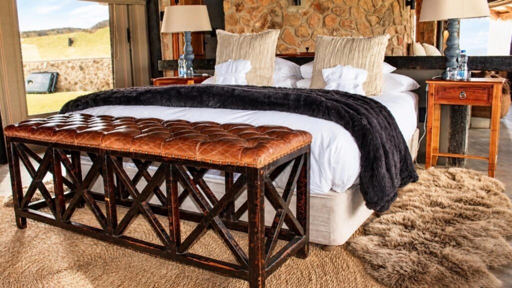 Luxurious master bedroom featuring a tufted leather bench and panoramic bushveld views at Sibani Lodge