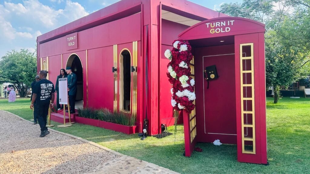 Striking red and gold "Turn It Gold" brand activation lounge featuring a telephone box installation and floral arrangements at the Luxurious Marble Circus.