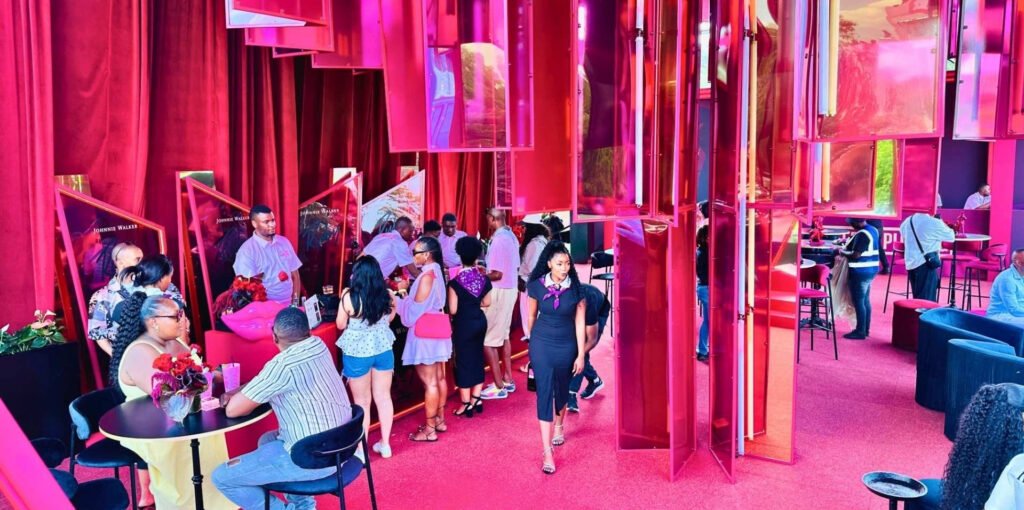 Guests enjoying the vibrant red and pink interior of the Johnnie Walker brand lounge at the Luxurious Marble Circus festival.