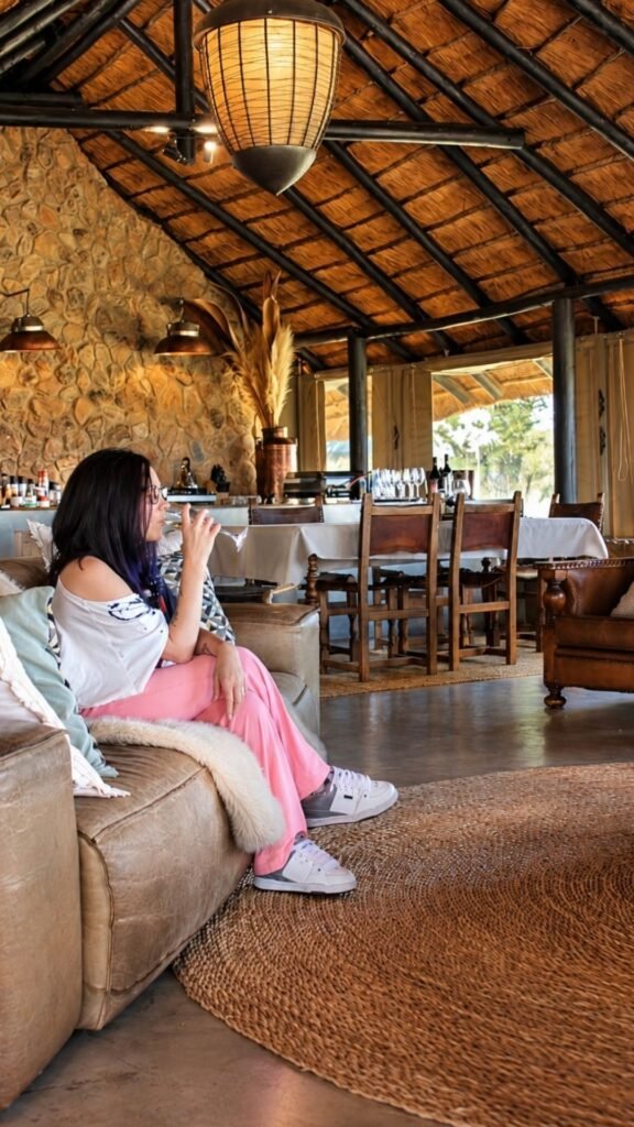 Claudia relaxing on a leather sofa inside the stylish lounge of Sibani Lodge private villa with thatched ceiling