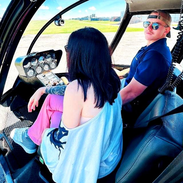 Claudia Sherrin seated in the front of a Helivate helicopter with pilot Rory Root at the controls on the tarmac at Jack Taylor Airport.