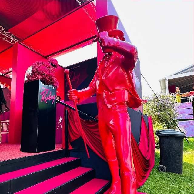 A striking red ringmaster statue holding a cane outside the Johnnie Walker activation area at the Luxurious Marble Circus.