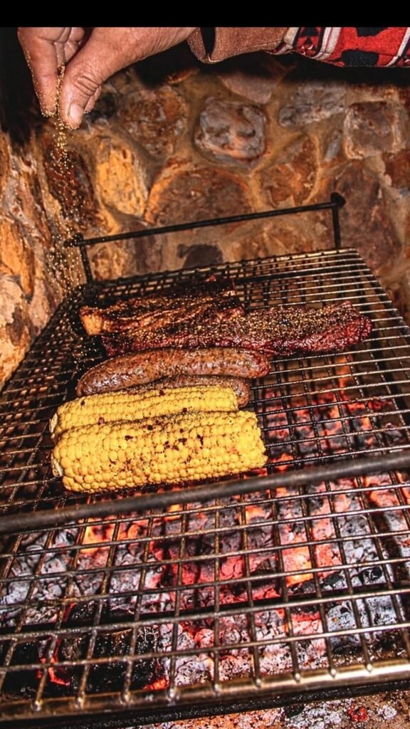 Steak, boerewors and corn grilling over open coals in the private courtyard of Sibani Lodge