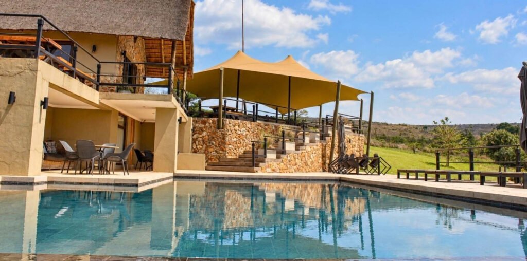 Infinity pool with beige shade sails and stone steps overlooking the Magaliesberg