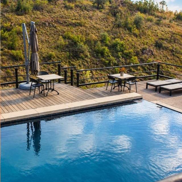 Wooden deck with loungers next to the infinity pool overlooking the Magaliesberg valley