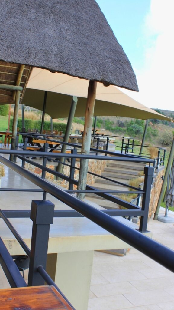Thatched outdoor dining and lounge area with views of the Magaliesberg at Sibani Lodge