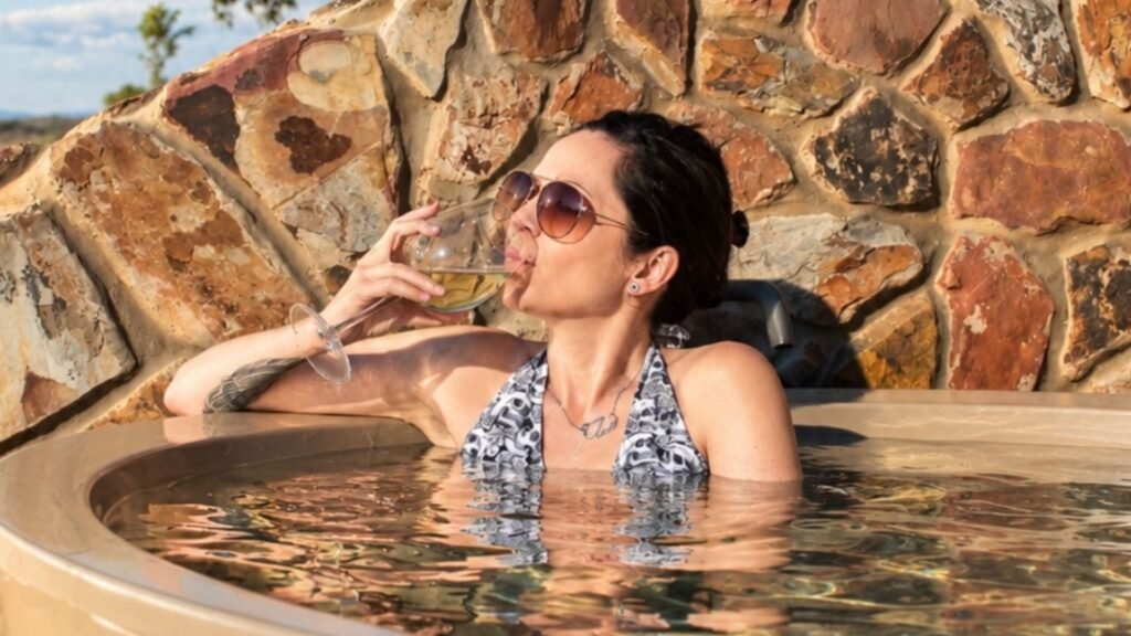 Claudia relaxing in the fire-heated hot tub with a glass of white wine at Sibani Lodge private villa