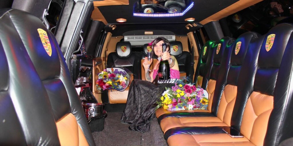 Claudia Sherrin seated in the Luxury Limousines Porsche Cayenne holding a bottle of champagne and crystal flute amid floral arrangements
